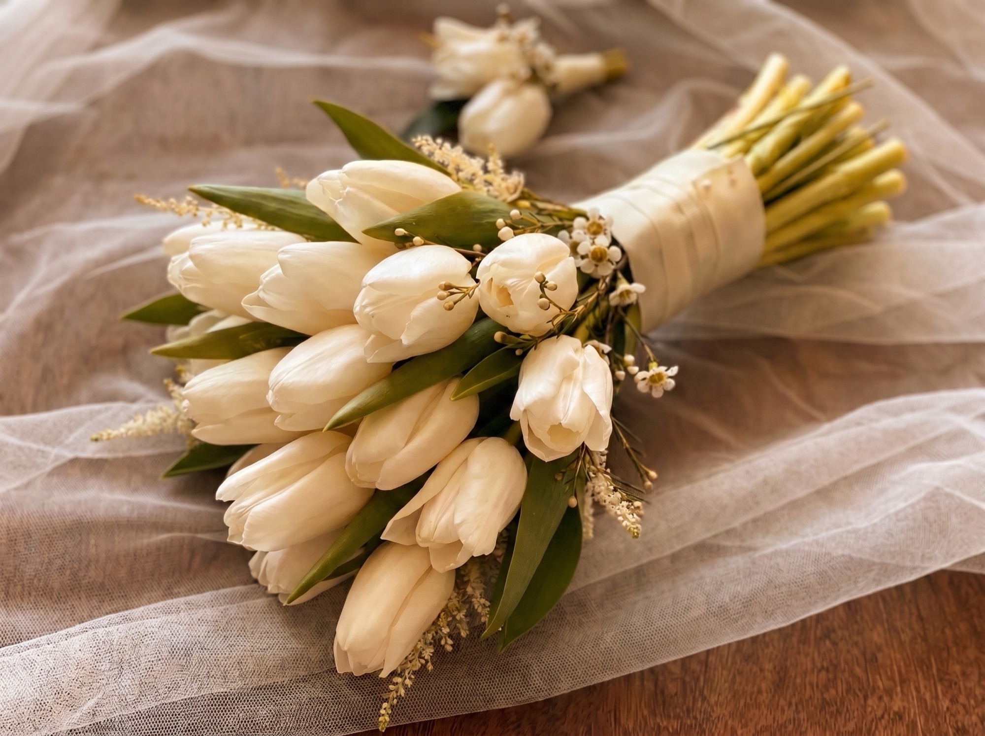 A bridal bouquet of white tulips resting on tulle