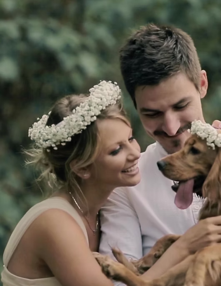 A couple laughing together with their dog on their wedding day