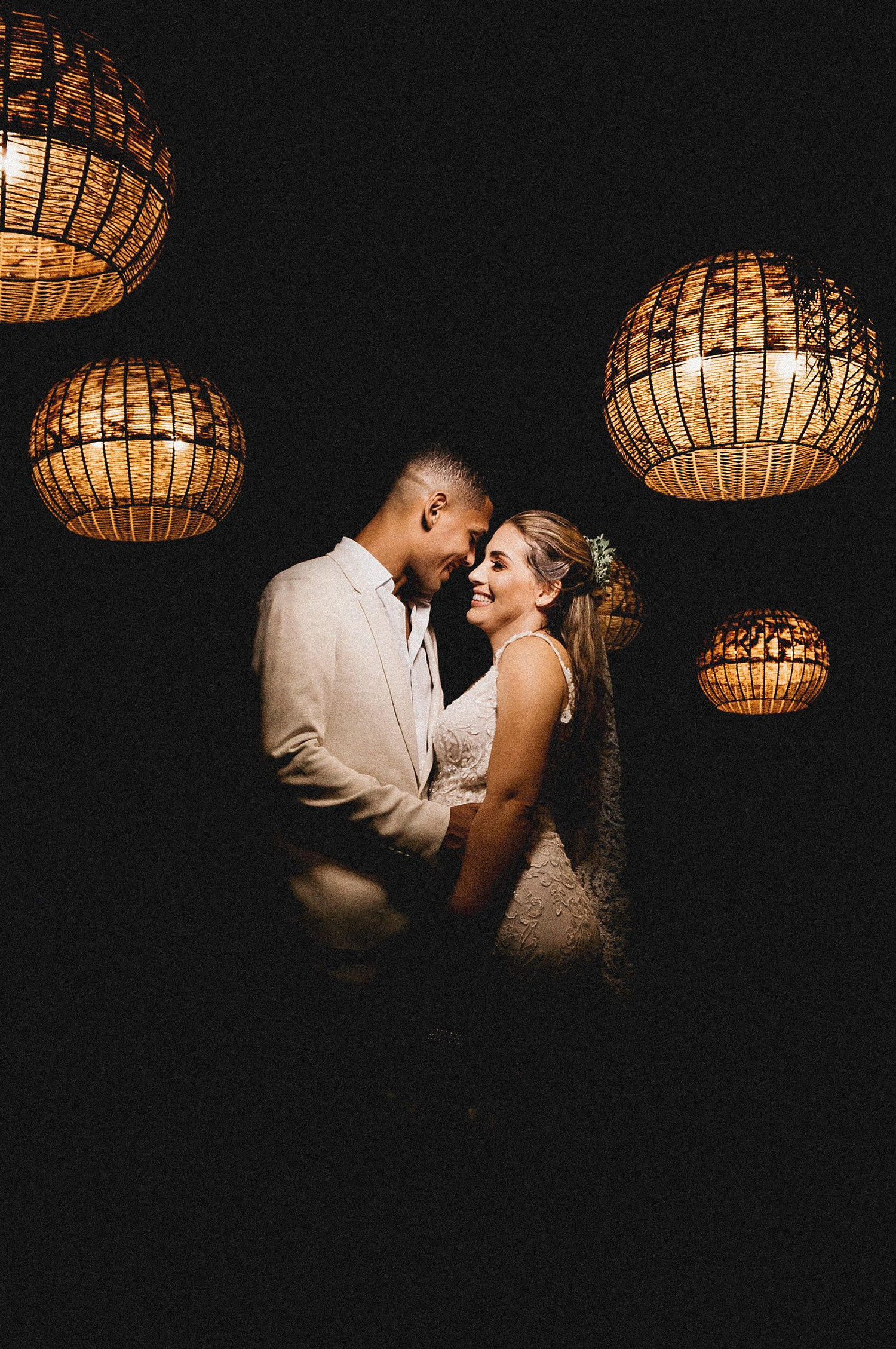 A couple sharing a quiet moment beneath glowing woven lanterns