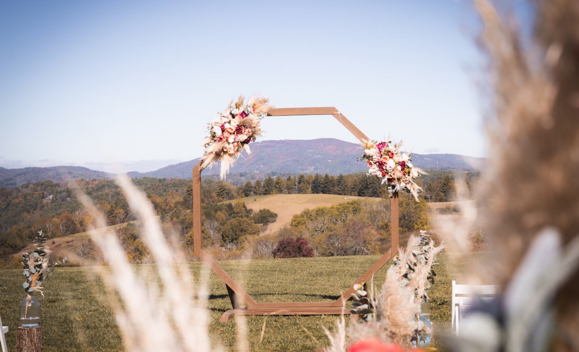 An outdoor ceremony arch set against the Blue Ridge mountains at golden hour