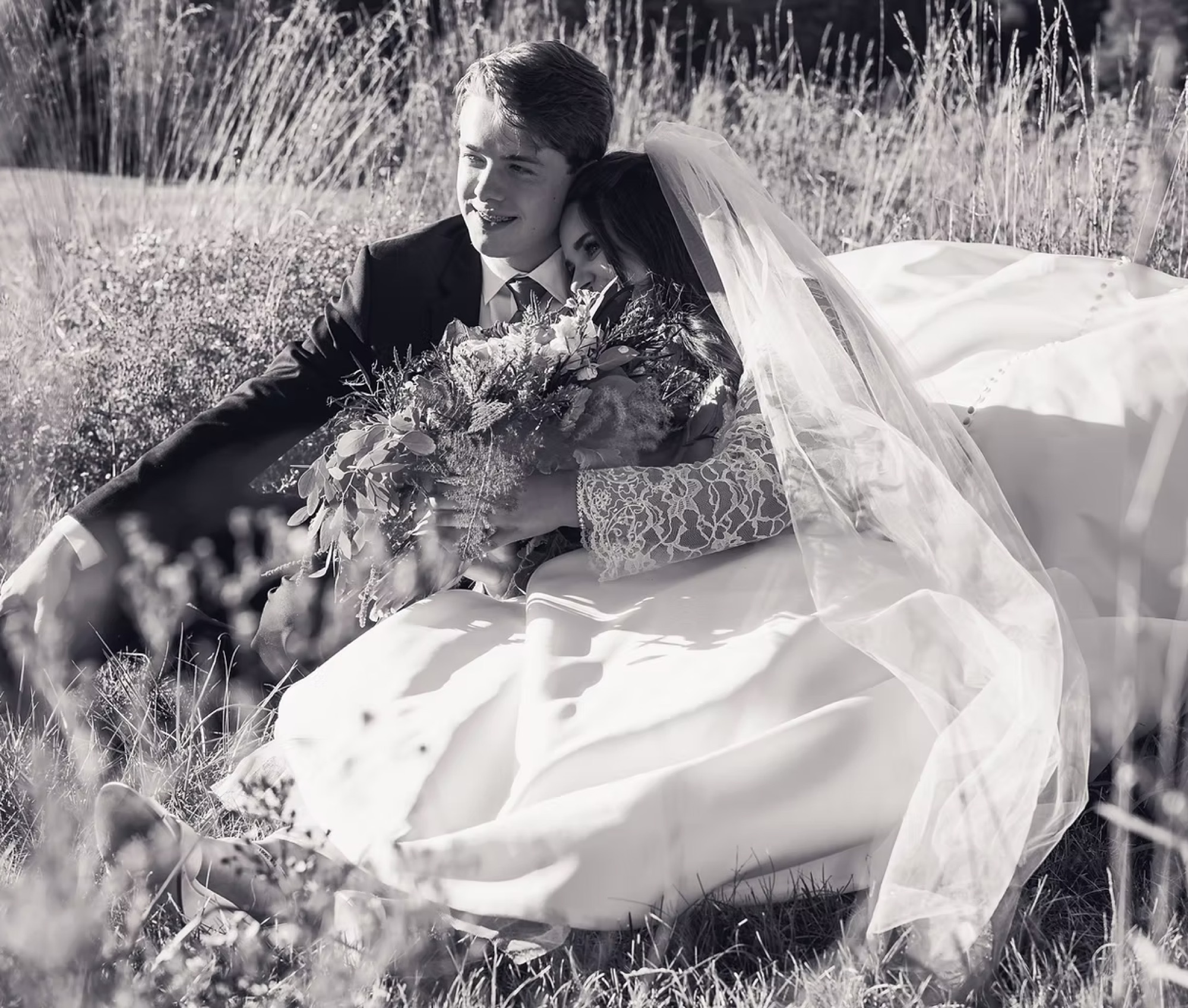 A newly married couple resting together in a wildflower field