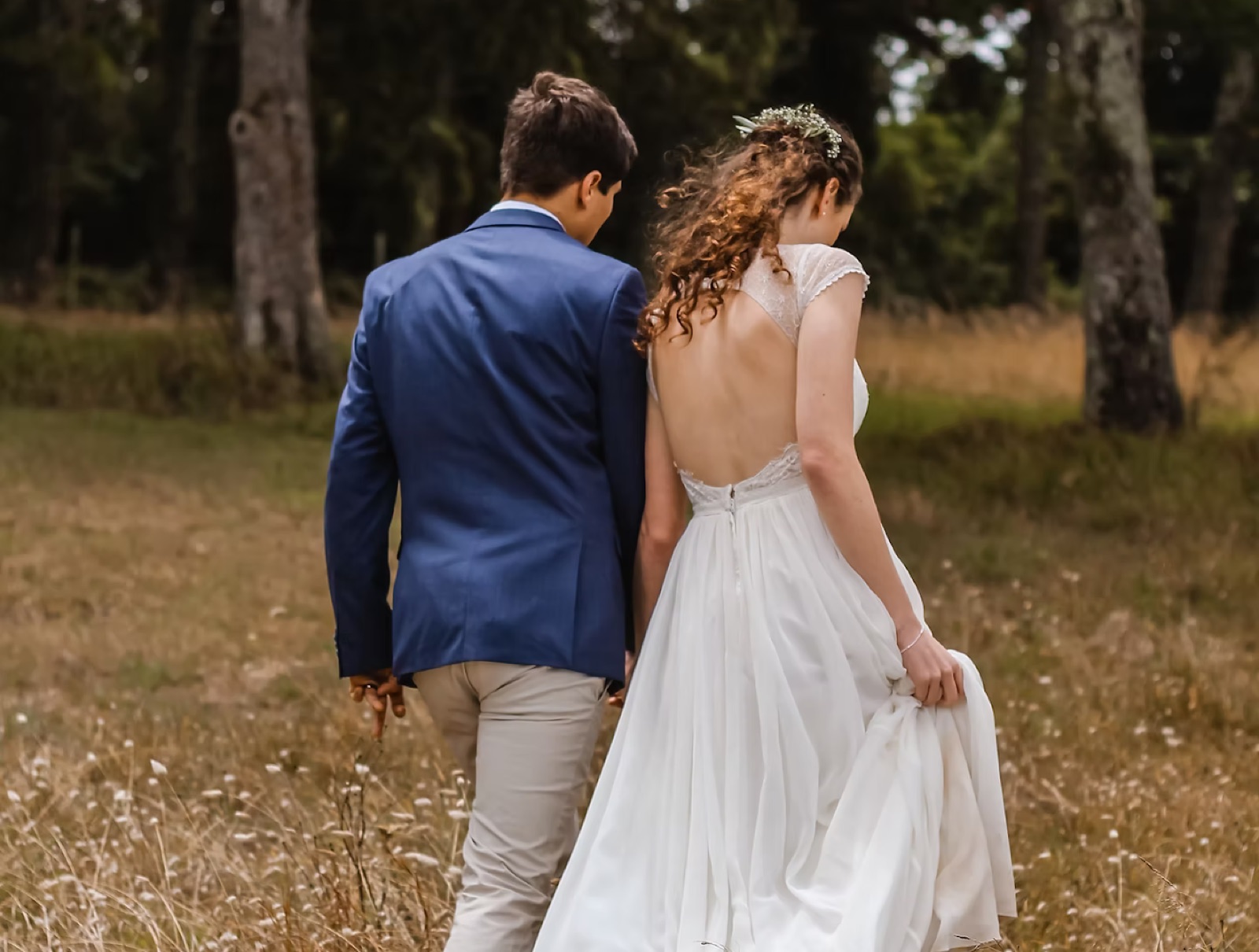 A couple walking through a meadow after their ceremony